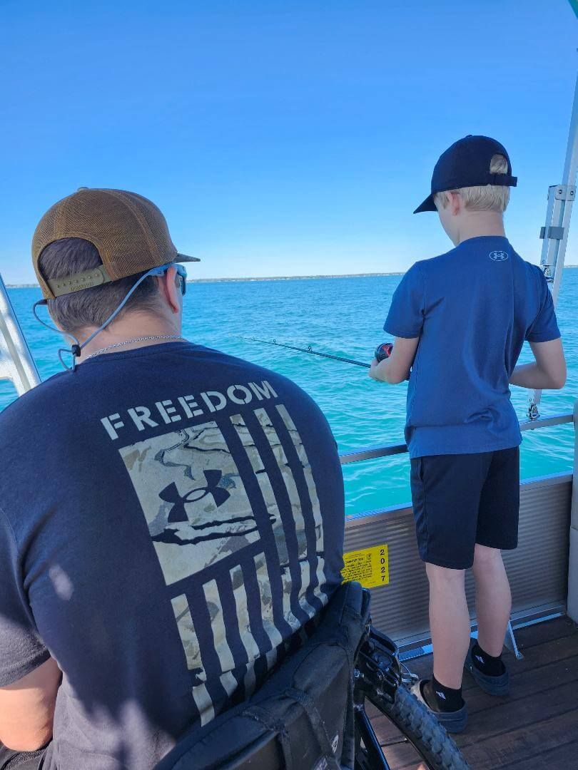 Man and child fishing on a boat. Man in wheelchair, wearing a 