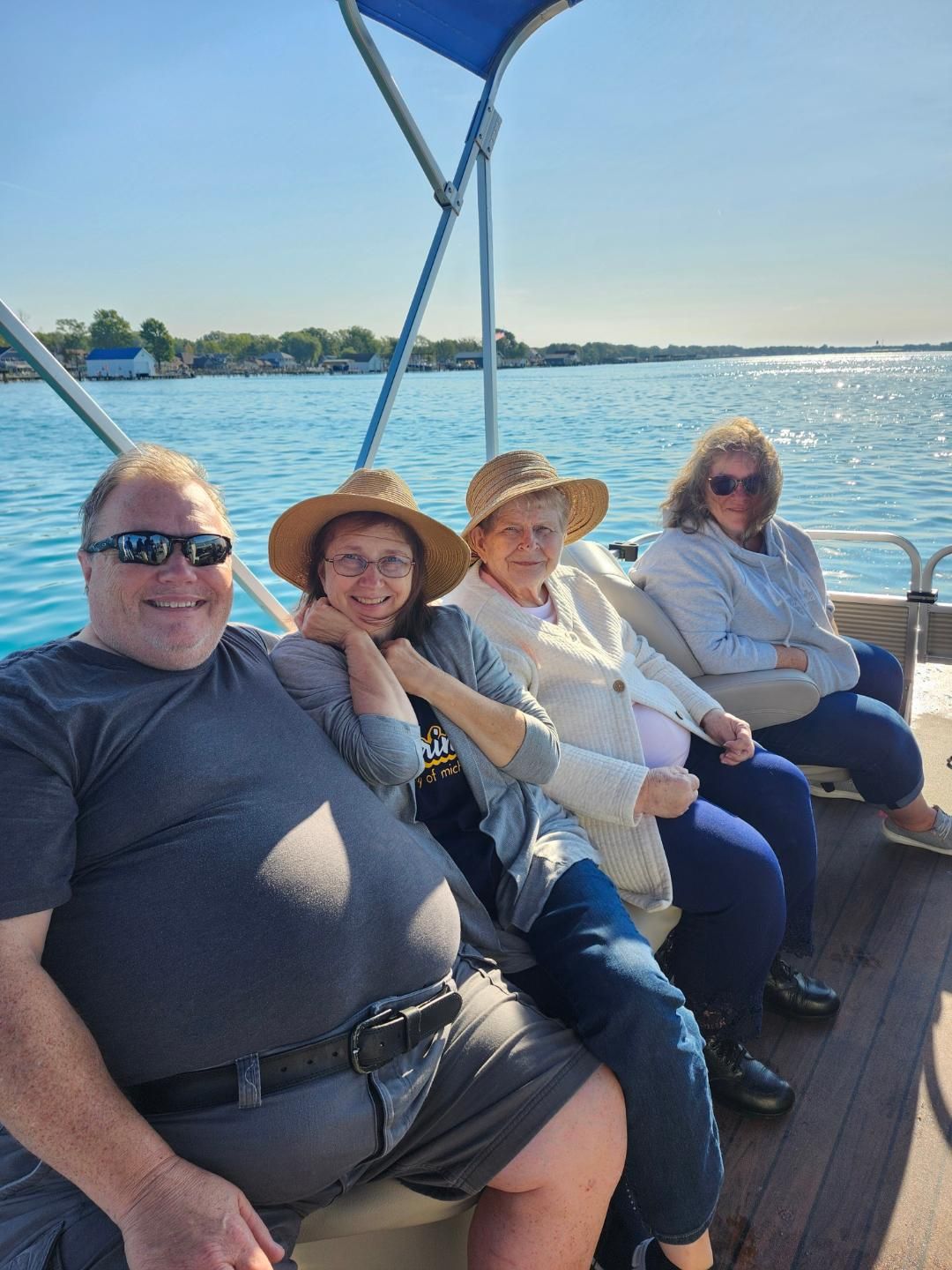Four people sit on a pontoon boat, enjoying a sunny day on the water.
