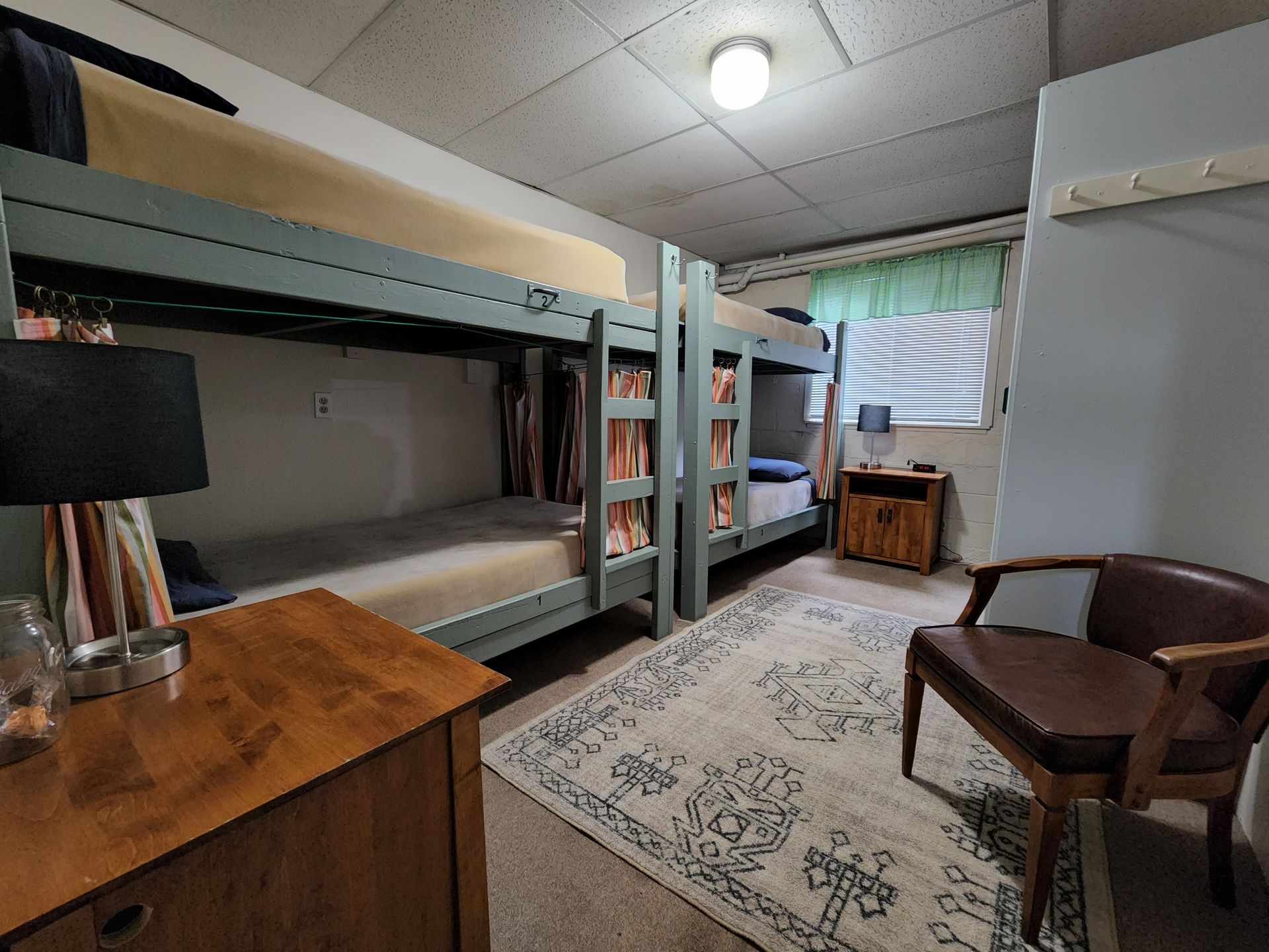 A bedroom with bunk beds , a nightstand , and a window.