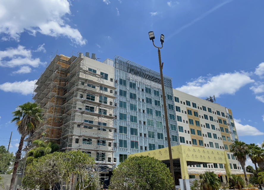Multi-story apartment building with blue-green windows under a bright blue sky.