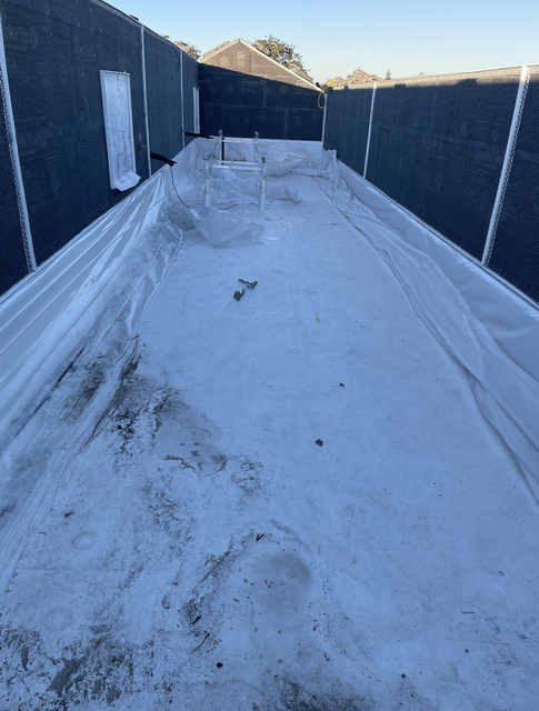 Snow-covered rooftop walkway with black walls and a central raised structure at sunset