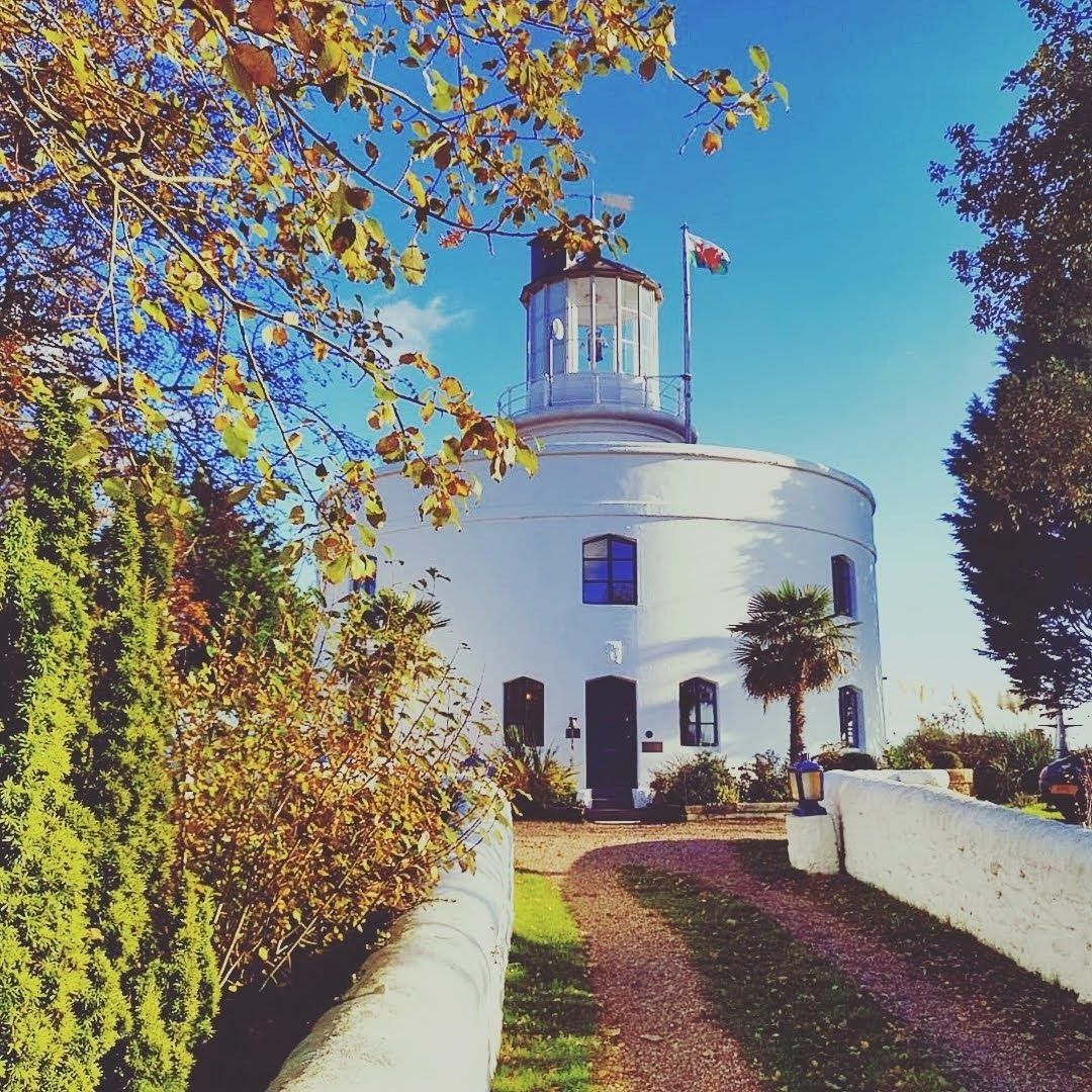 The front of the West Usk Lighthouse in autumn, with the Welsh flag flying.