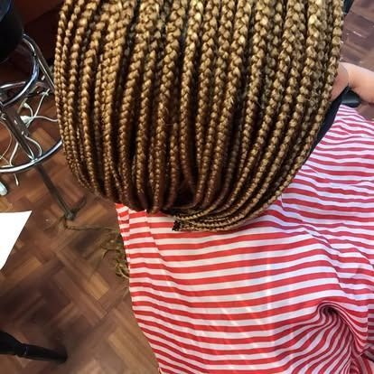Person with blonde box braids wearing a red-and-white striped shirt, viewed from behind indoors