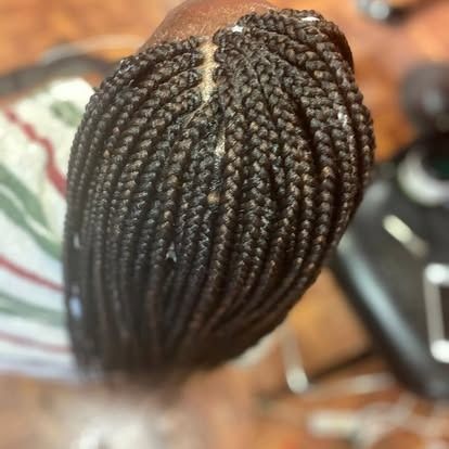 Close-up of neatly braided dark hair with a parting on the scalp.