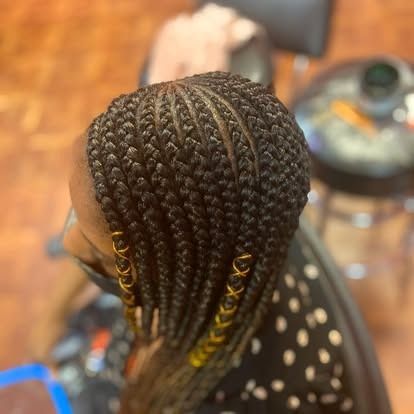 Top view of neatly braided hair with gold accents, worn indoors near a salon chair