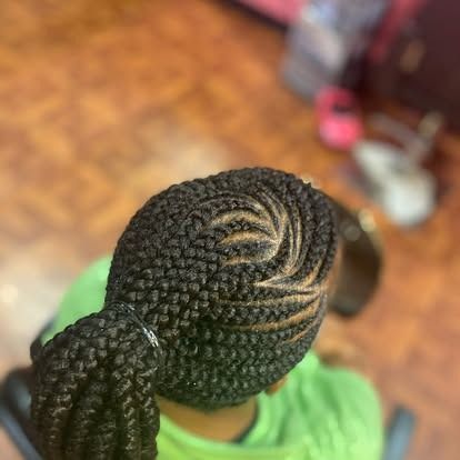 Top view of a person with intricate braided hair, wearing a green shirt indoors