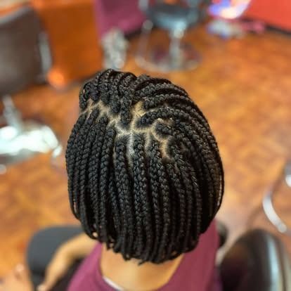 Close-up of a braided hairstyle with neat cornrows on a person seated in a salon chair