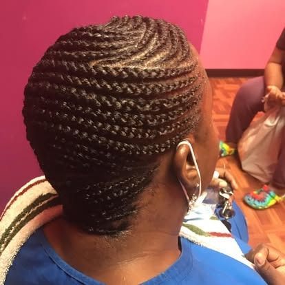Close-up of a braided hairstyle from the back, with a small hoop earring visible in a brightly lit room