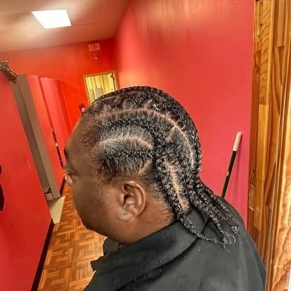 Person with braided hair in a red hallway, viewed from the side.