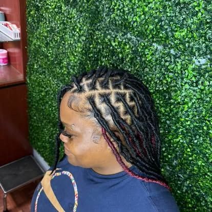 Side-profile portrait with braided hair against a green leafy wall backdrop