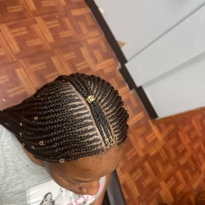 Close-up of braided hair styled into neat cornrows with a center part on a parquet floor background