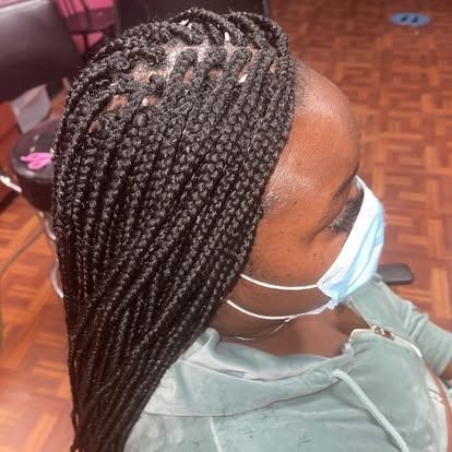Braided hair styled in long plaits, viewed from above, with a blue face mask indoors.