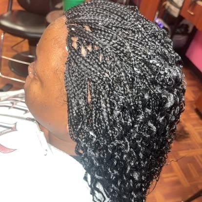 Side view of braided black hair styled into long twists with loose curls at the ends.