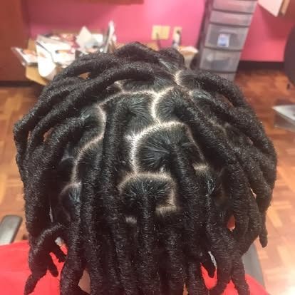 Top view of short black twisted locs against a red background