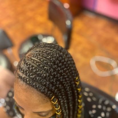 Close-up of braided hair with gold accents at a salon chair