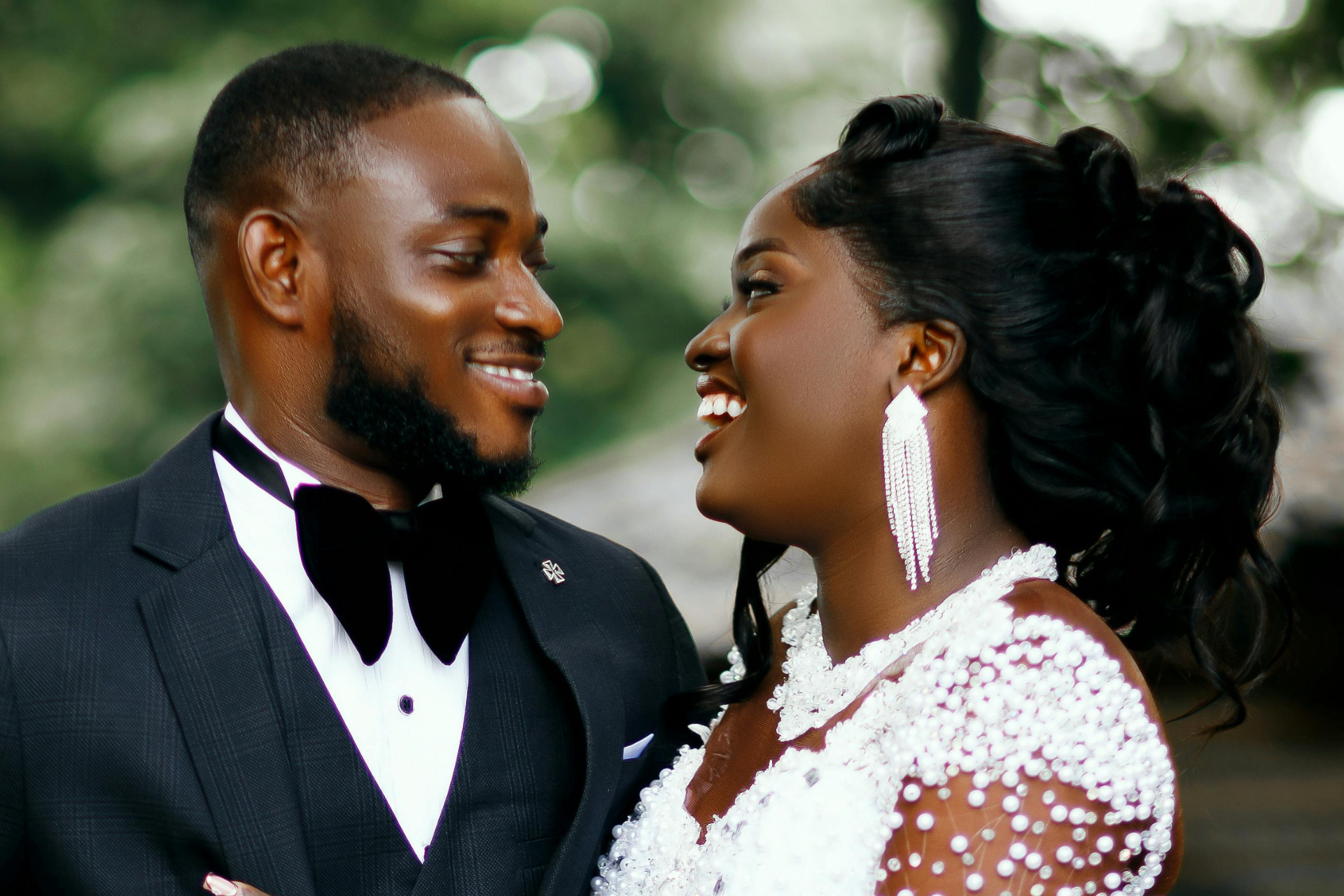 Smiling couple in formal black and white attire, facing each other at a wedding.