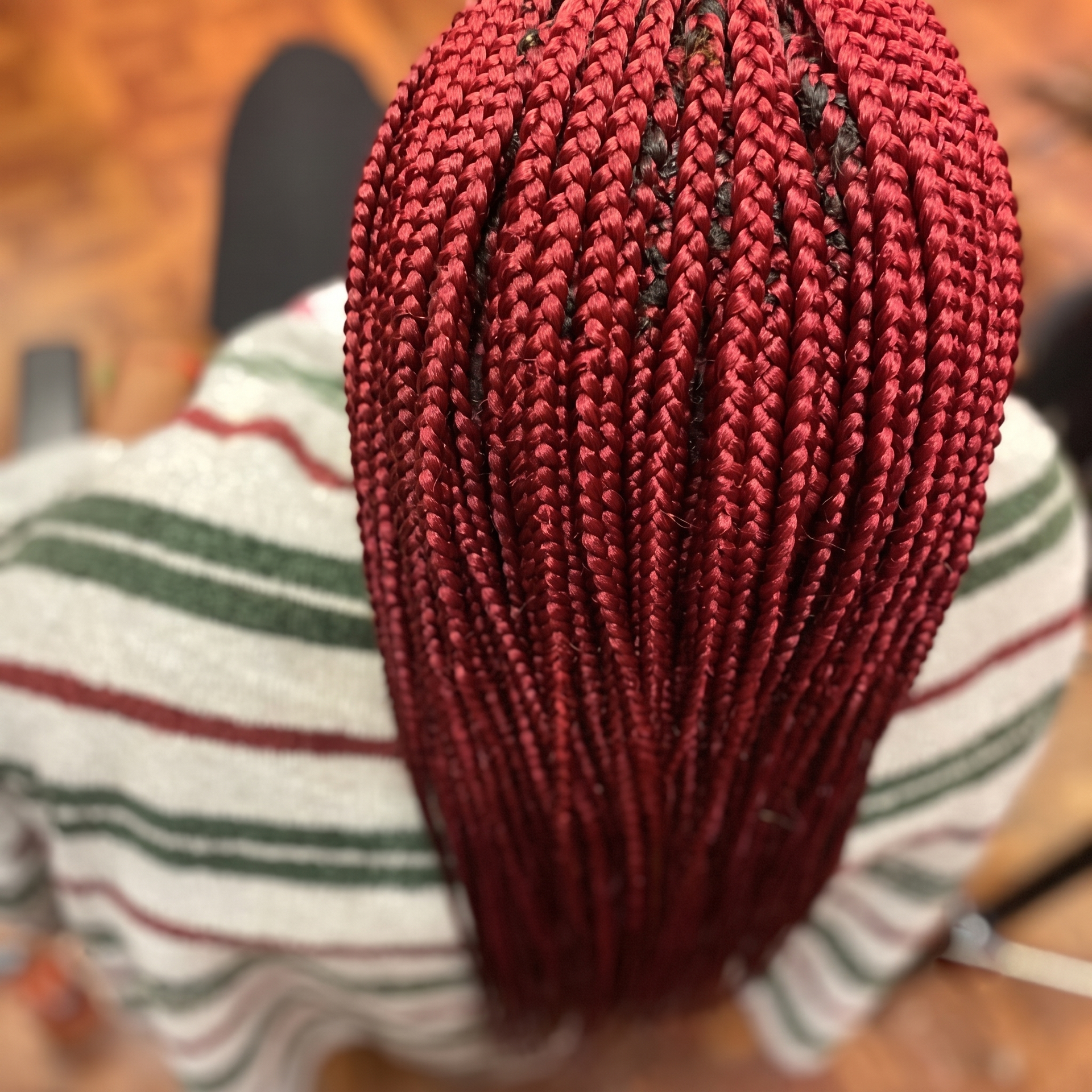 Close-up of long red braided hair from above, with a striped shirt visible underneath