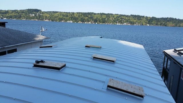 A curved blue corrugated metal standing seam roof is on a home. It has skylights. 