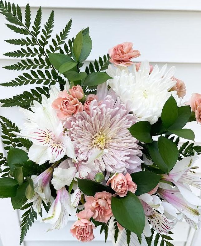 A bouquet of pink and white flowers is sitting on a white table.
