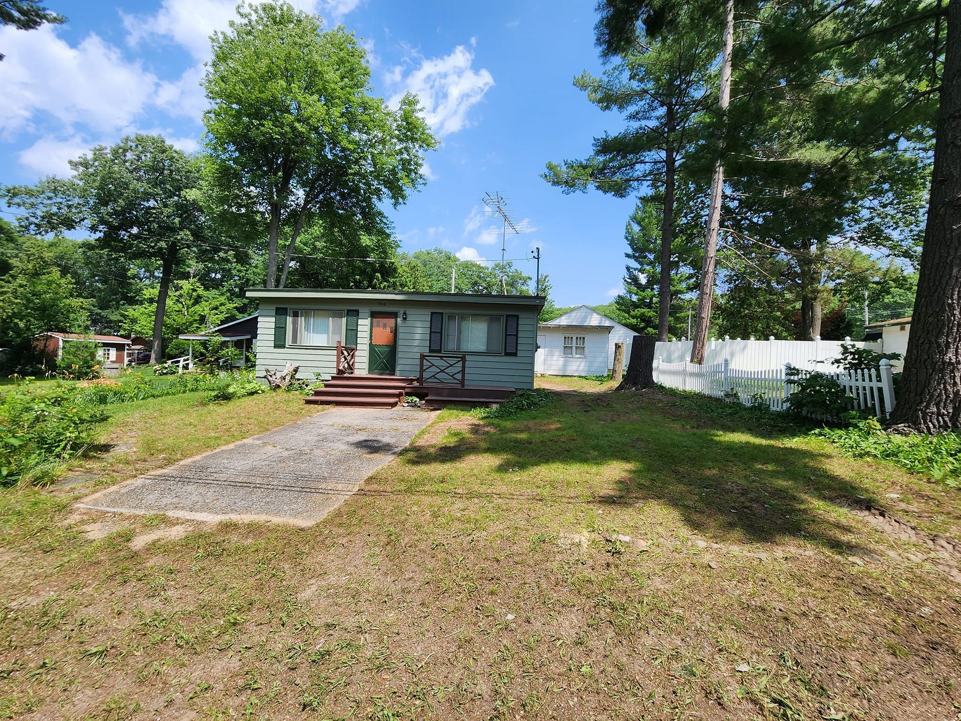 A small house is sitting in the middle of a lush green field surrounded by trees.