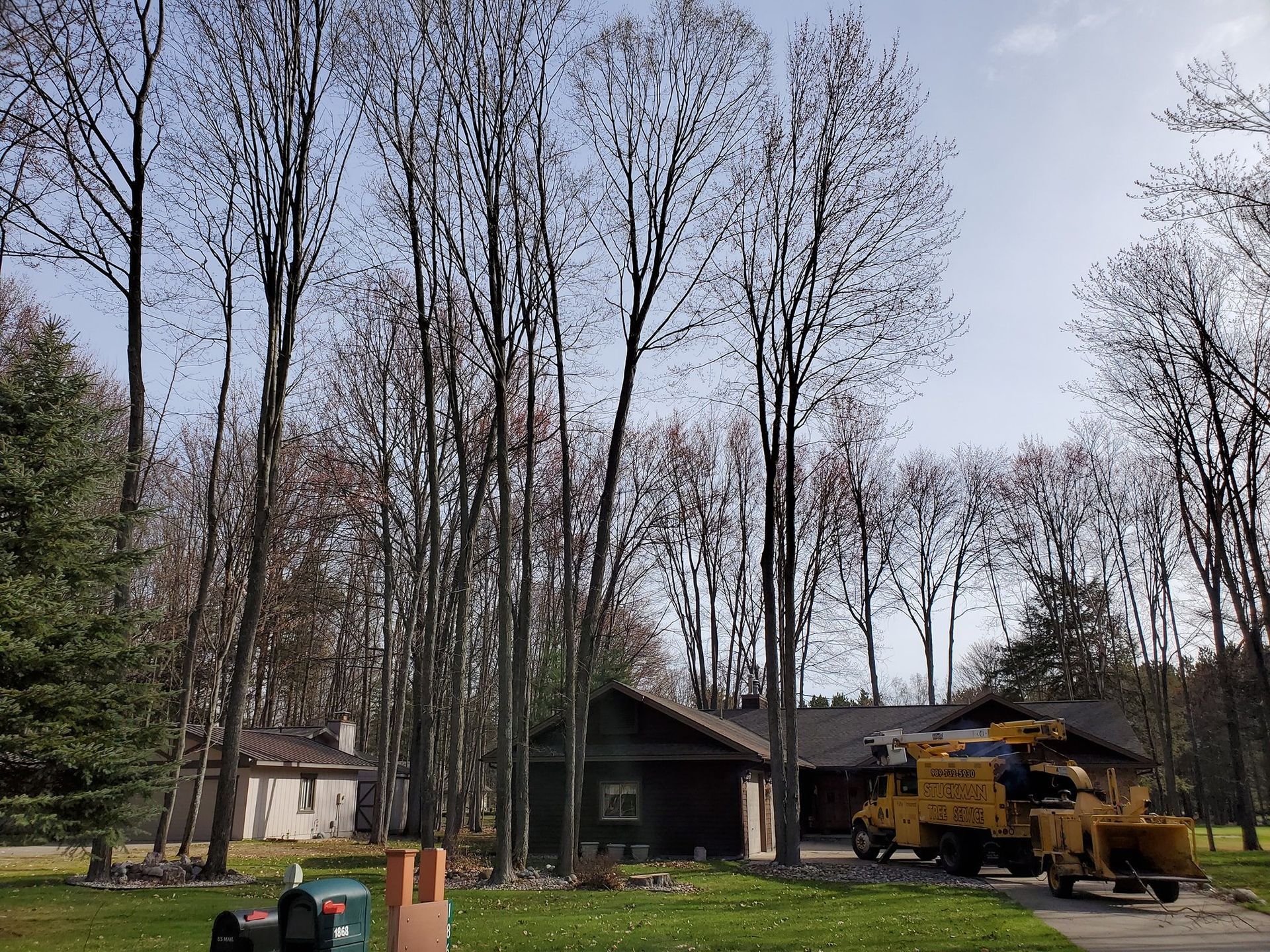 A yellow truck is parked in front of a house in the woods.