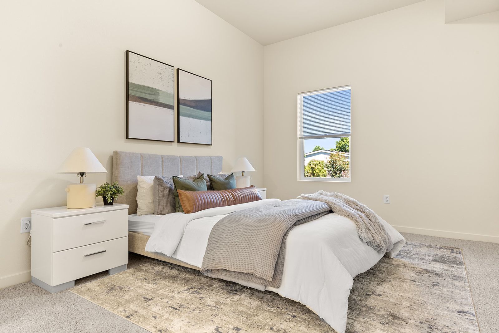 Bright modern bedroom with a white bed, bedside tables, and a patterned window shade.