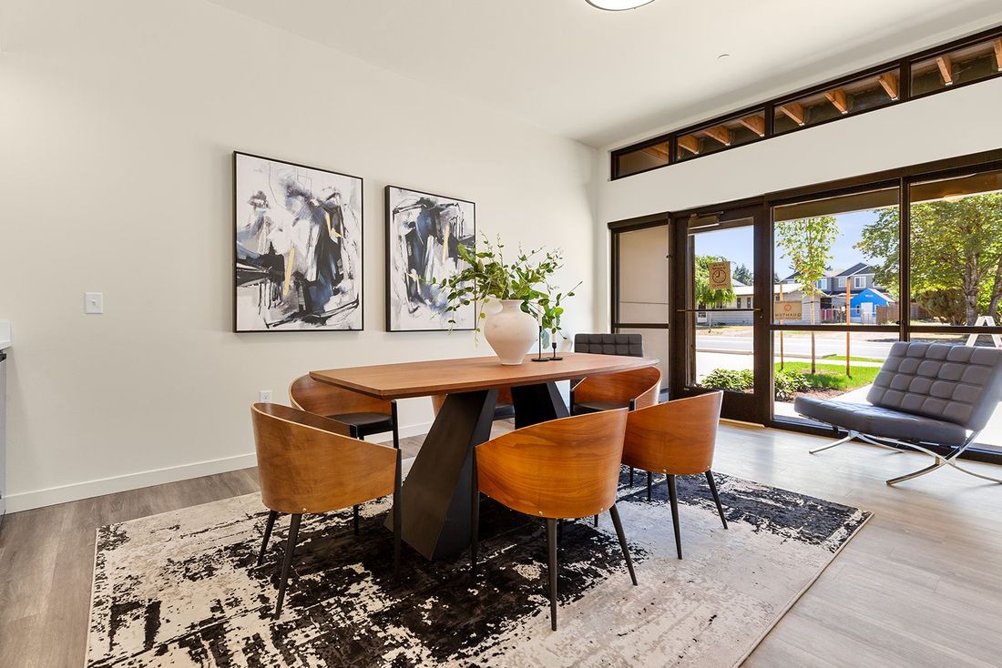 Modern dining room with wood table, four chairs, abstract wall art, and sliding doors to a sunny patio