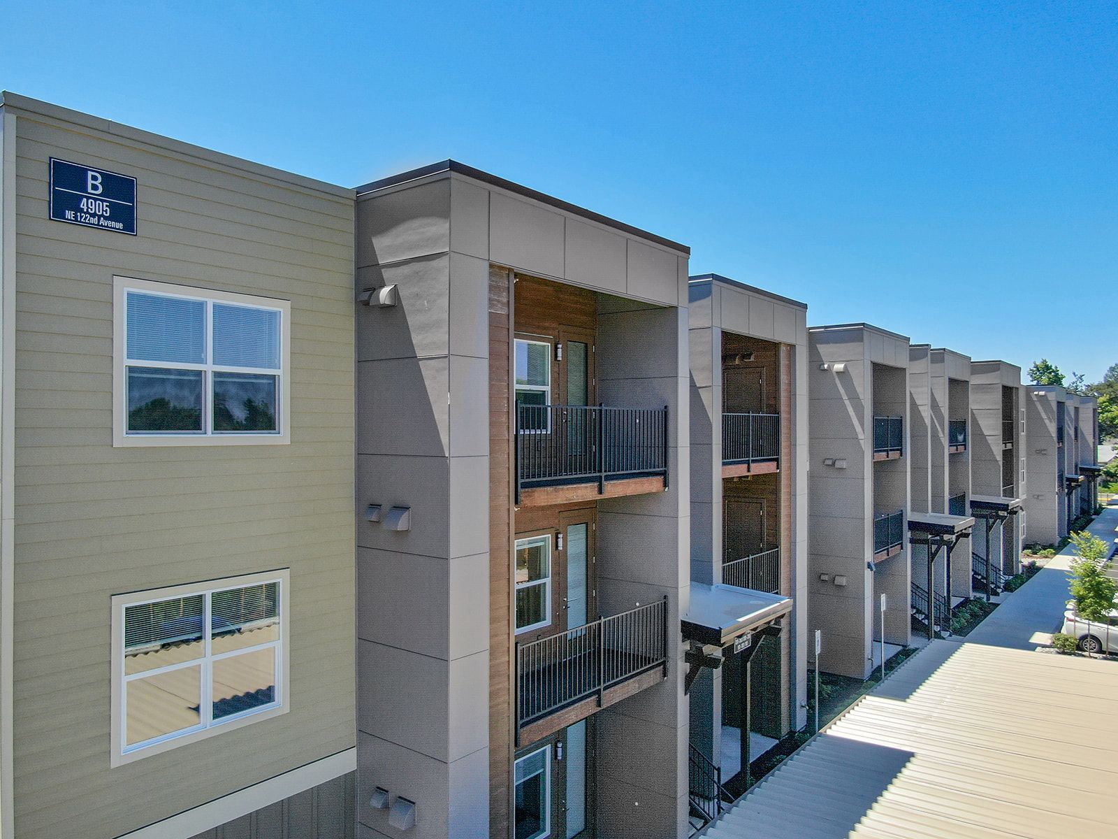 Apartment complex exterior with beige buildings, balconies, and blue sky