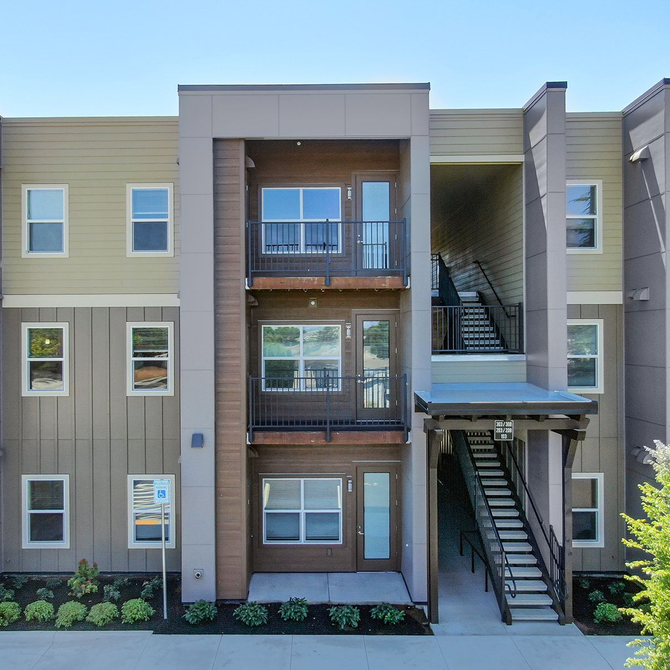 Modern apartment building facade with balconies and exterior staircases in daylight