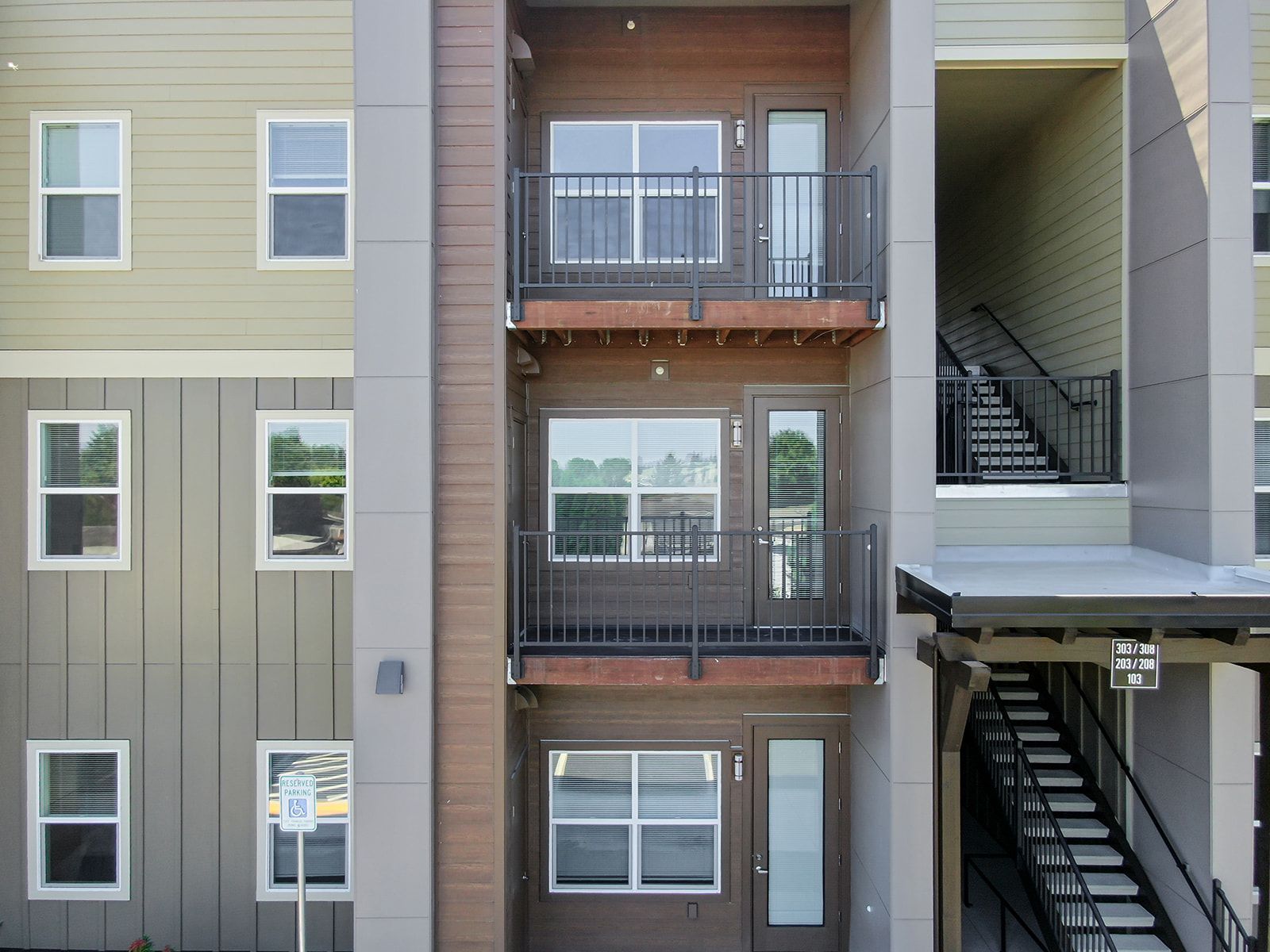 Apartment building exterior with balconies and outdoor staircases in beige and gray tones