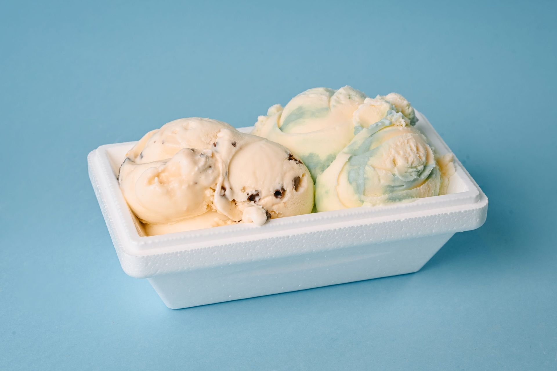 A white tray of assorted ice cream scoops on a light blue background