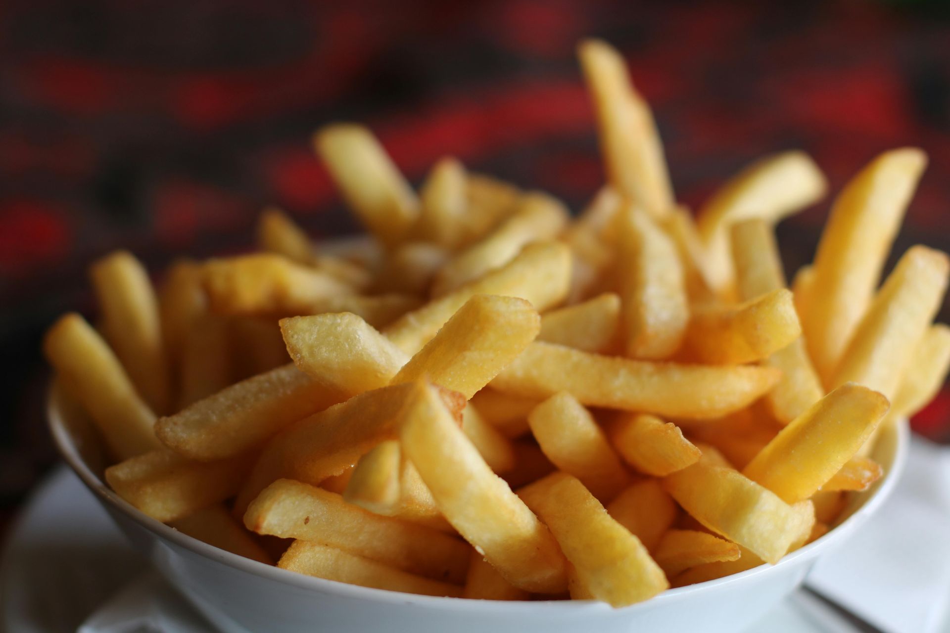 Bowl of golden French fries with a blurred dark background