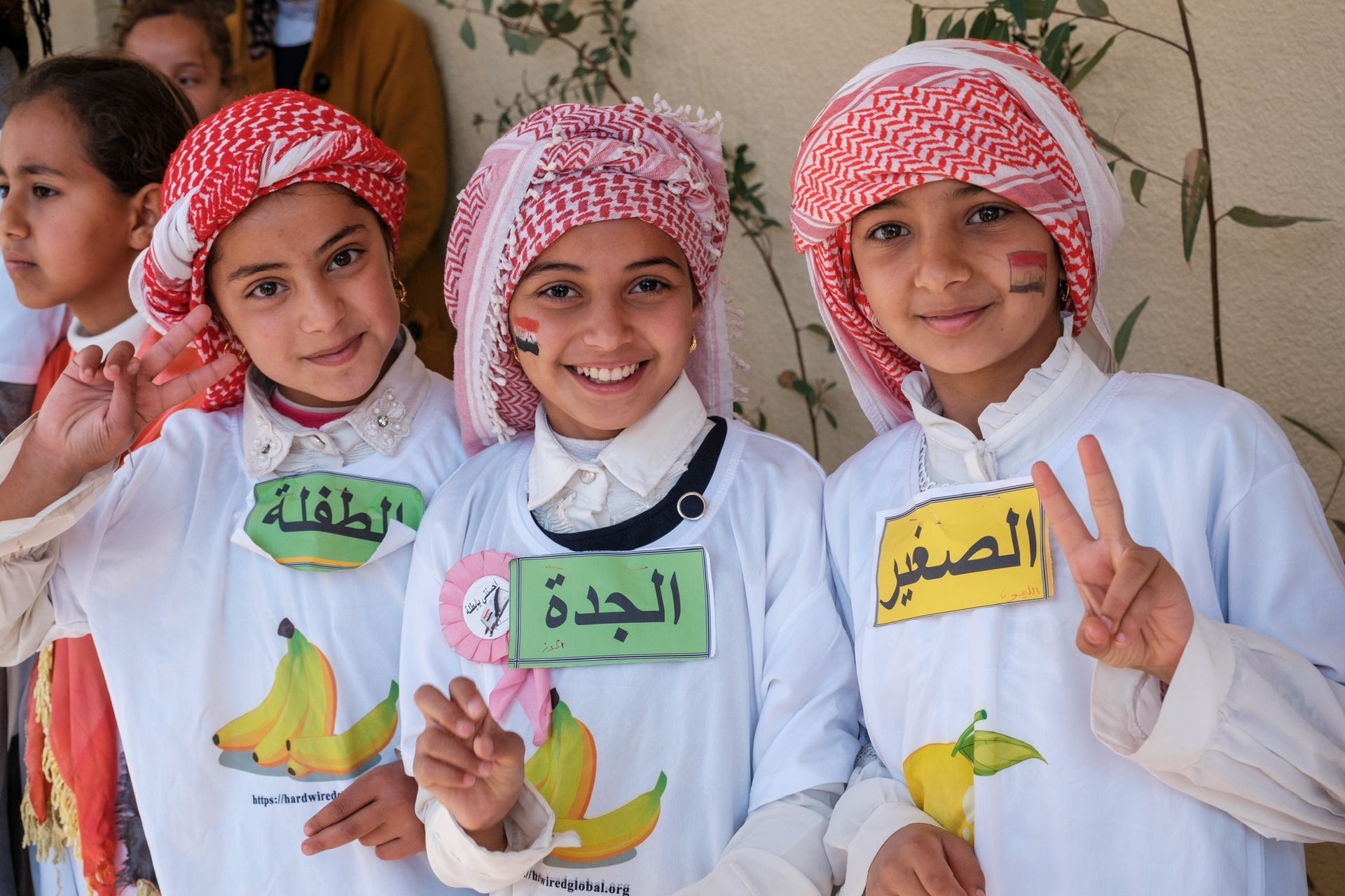 Humanitarian Programs in Iraq: Three children wearing shirts with arabic writing on them