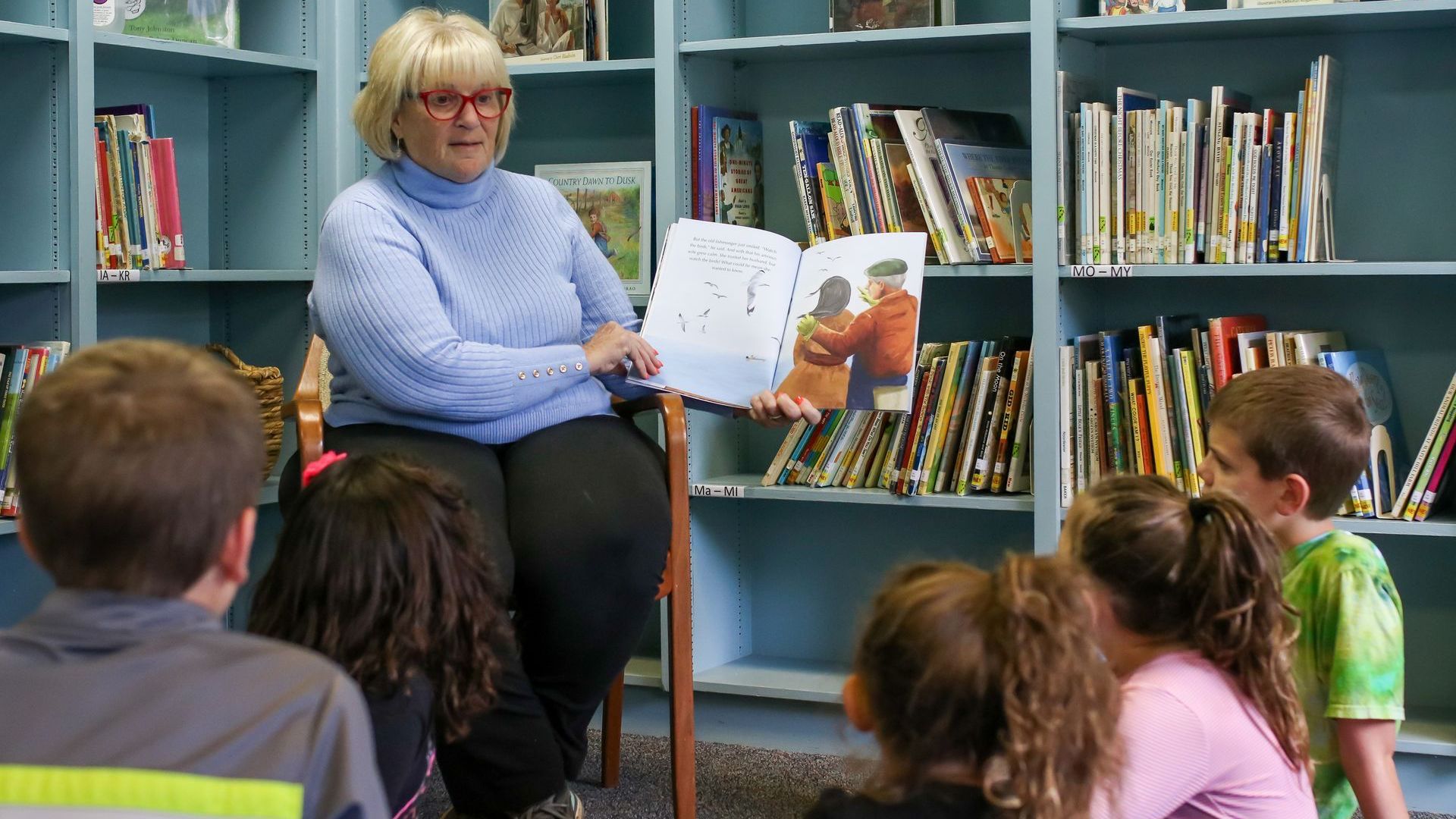 Human Rights Education & Training: A woman is reading a book to a group of children in a library.