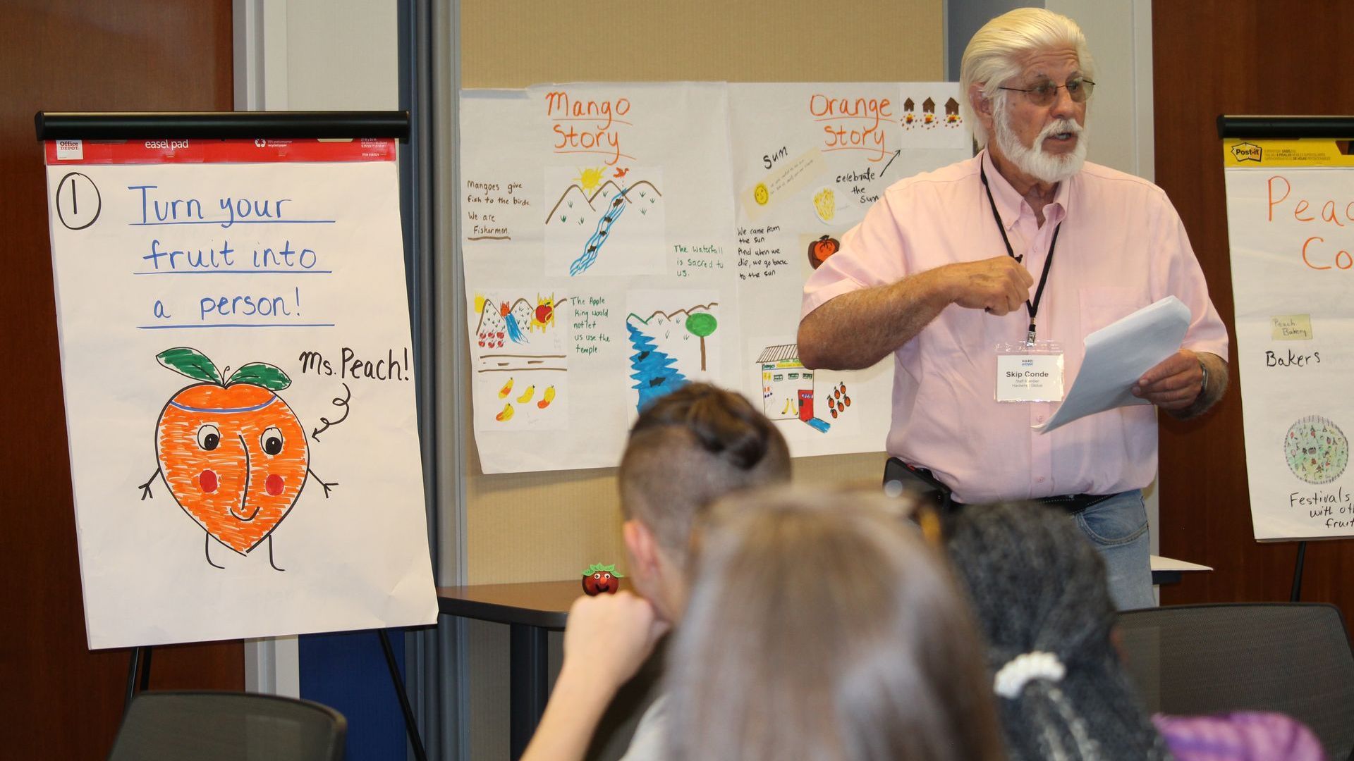 Human Rights Education & Training: A man in a pink shirt is giving a presentation to a group of children