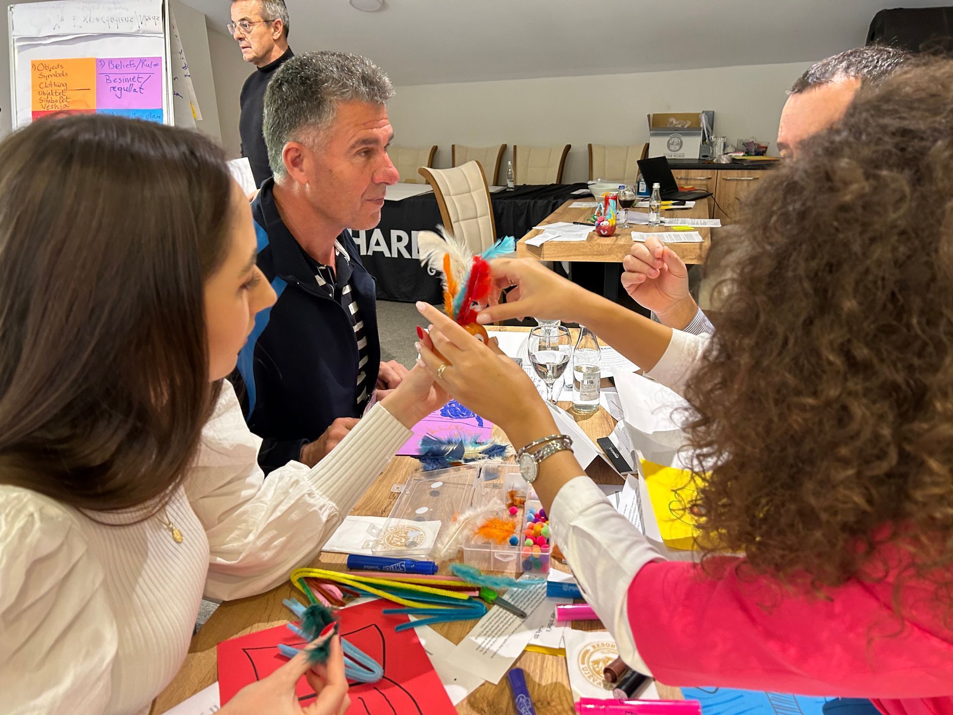 Programs for Refugees: A group of people are sitting around a table making crafts.