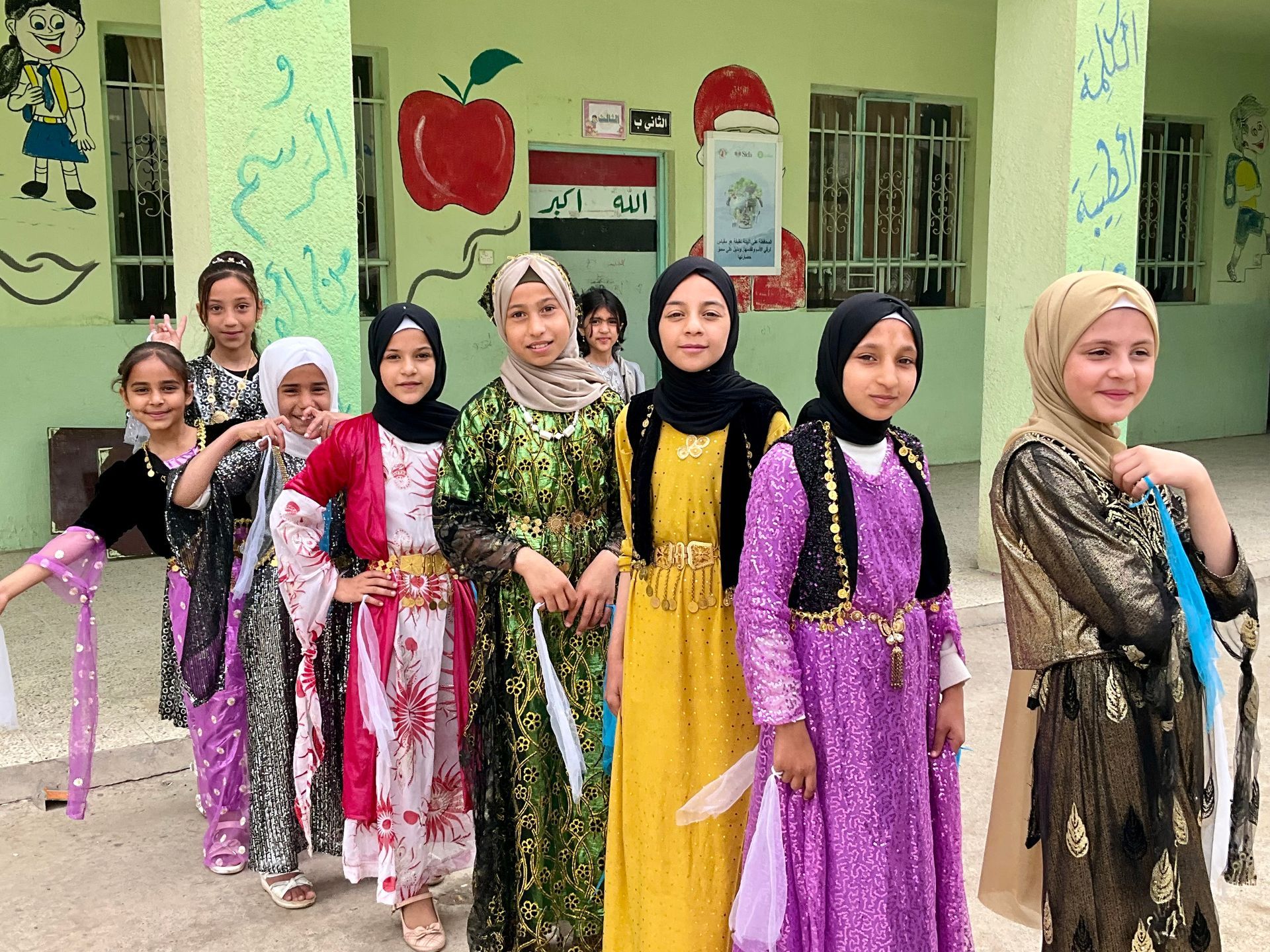 Humanitarian Programs Iraq: A group of young girls are standing in front of a building.