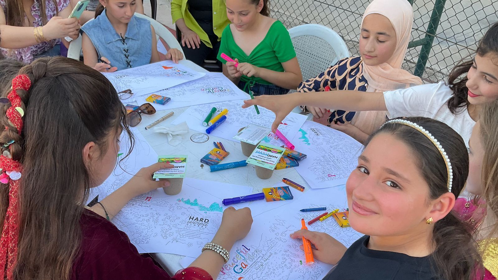 CRT: A group of young girls are sitting around a table drawing with markers.