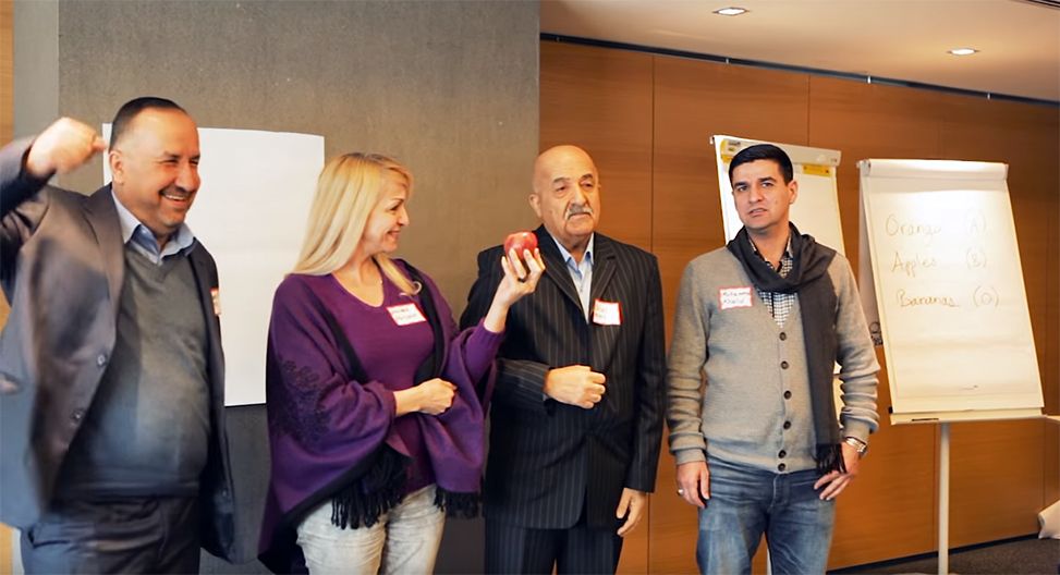 Human Rights Education: A group of people standing in a room with a woman holding an apple
