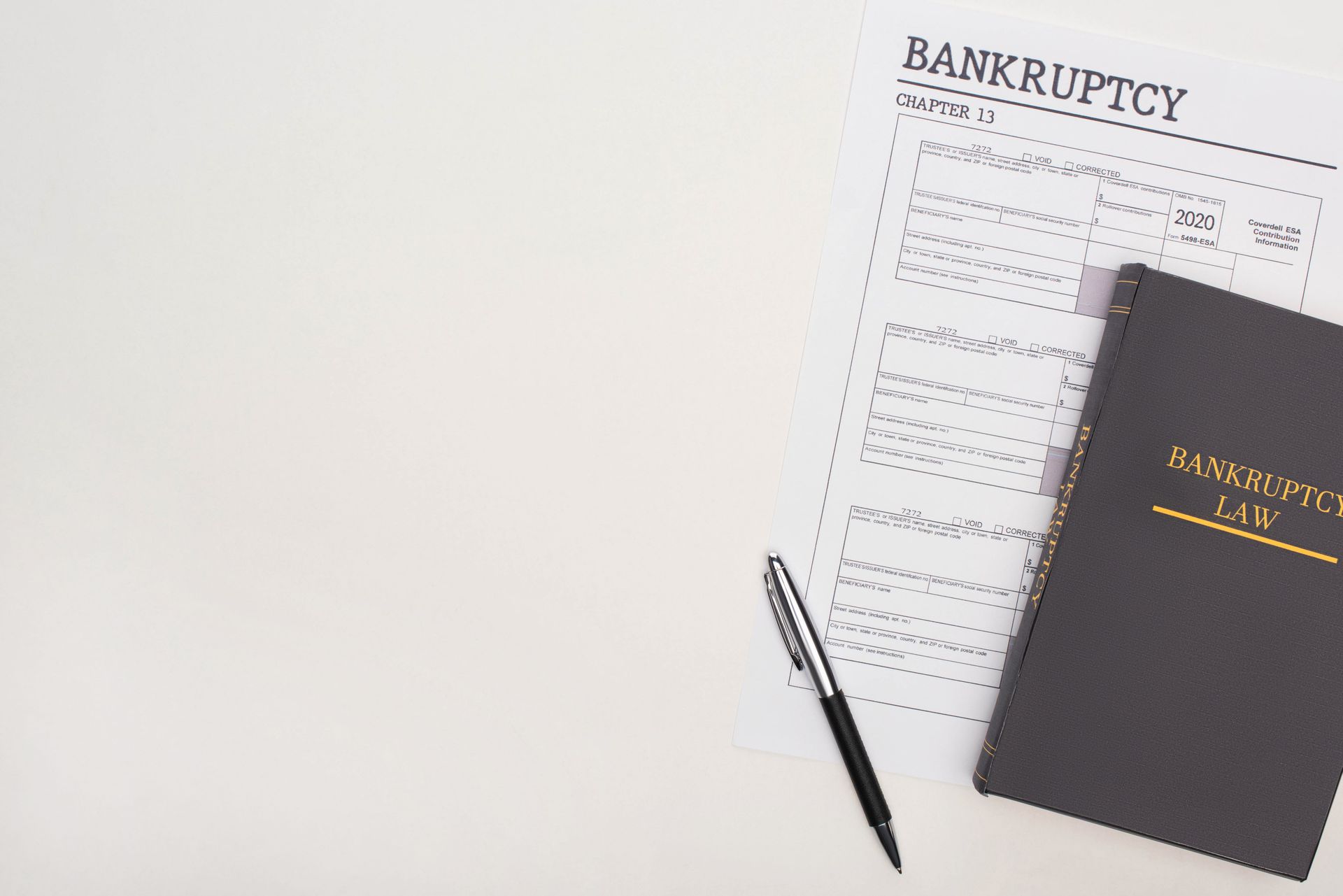 Bankruptcy paperwork beside a black notebook and pen on a white desk