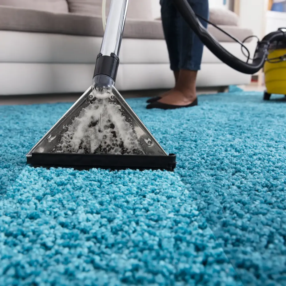 MB Carpet Cleaning- Cleaning a blue carpet with a vacuum cleaner.