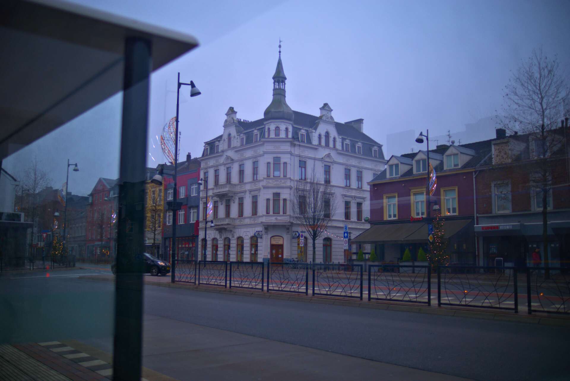 Street scene with historic white building, spire, and red buildings on a cloudy day.