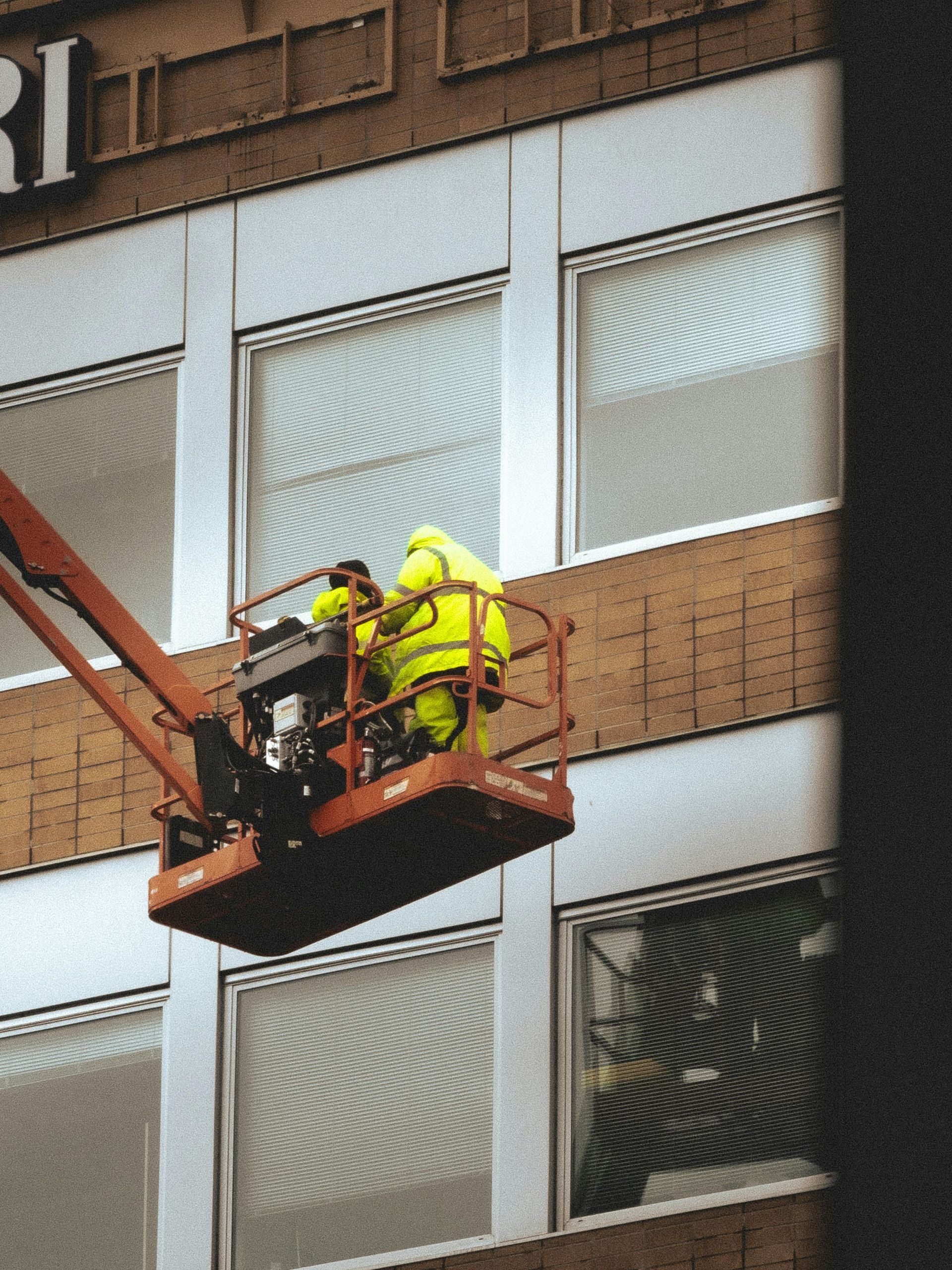 Een persoon op een hoogwerker voor een gebouw