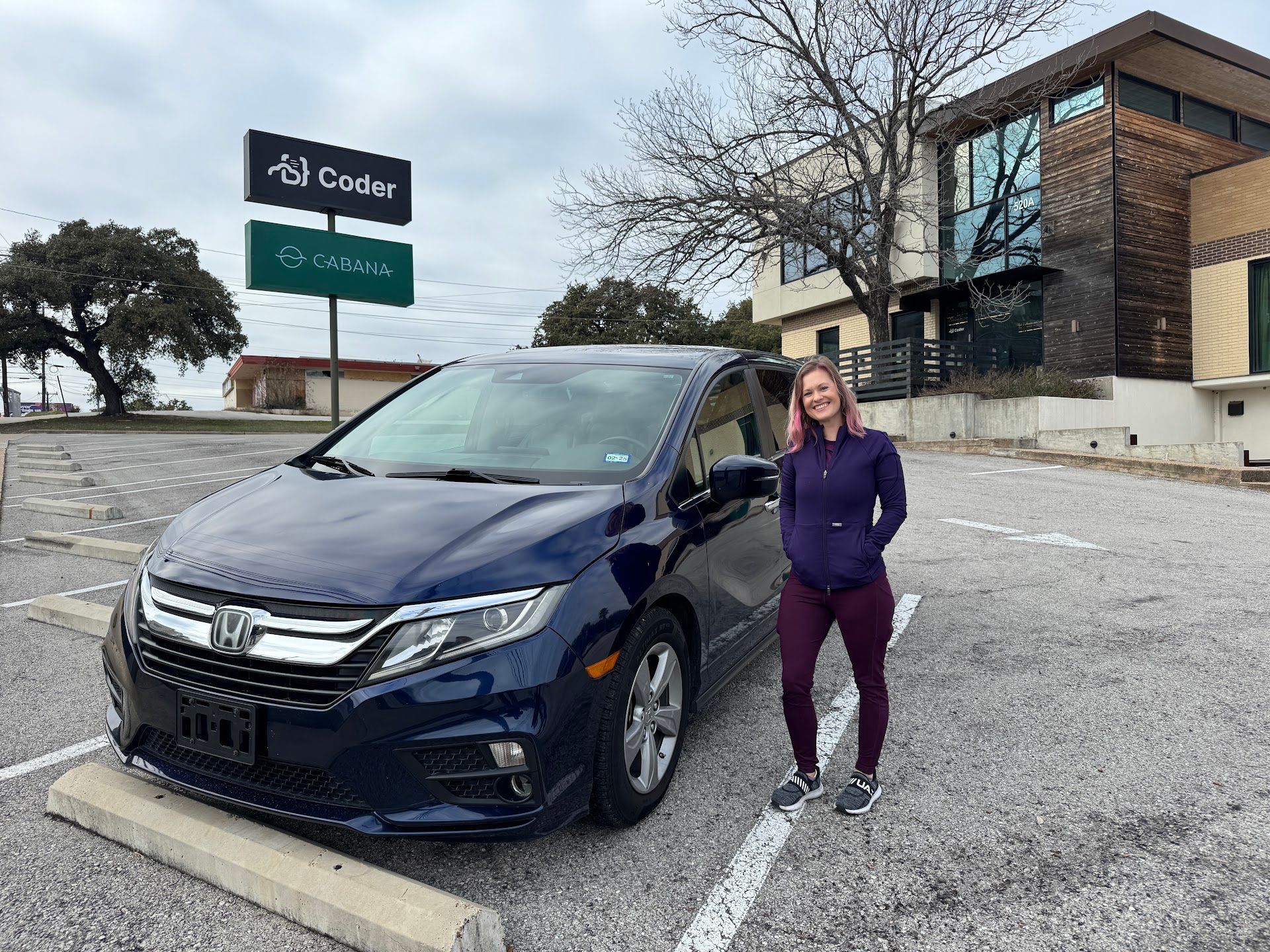 Woman standing beside a dark blue car in a parking lot near a Cenda sign | Everflux Service.