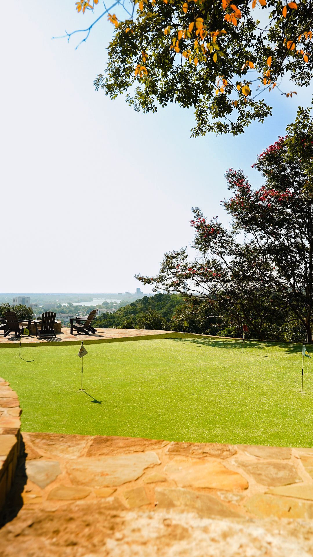 Sunny garden lawn with trees, stone patio, and distant ocean view