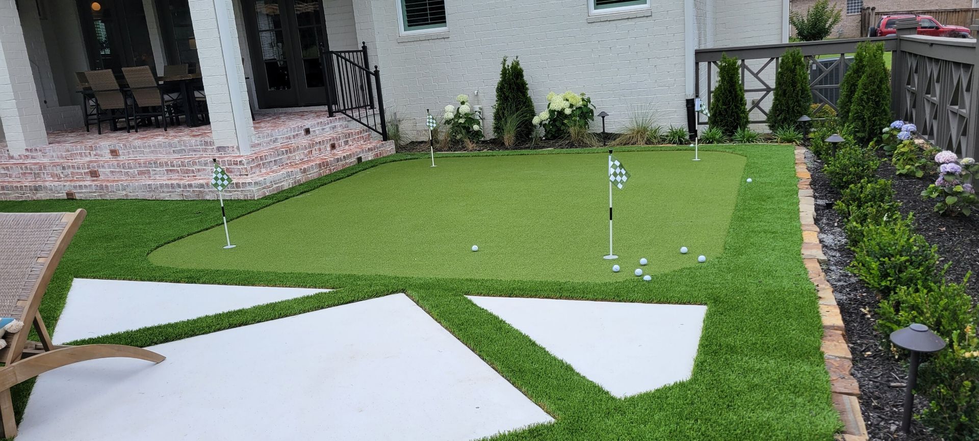 Backyard lawn with large white stepping stones and a house patio in the background