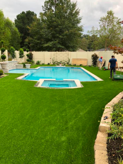 Backyard with bright green lawn, swimming pool, and two people near the right side