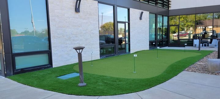 Modern building exterior with a small green lawn and walkway beside large windows