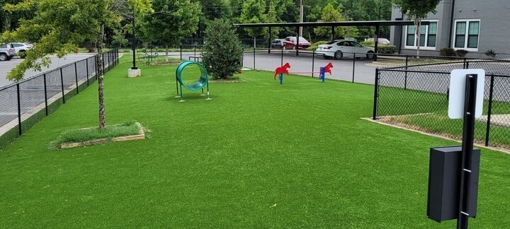 Grassy playground with colorful play equipment, fenced yard, and a building in the background