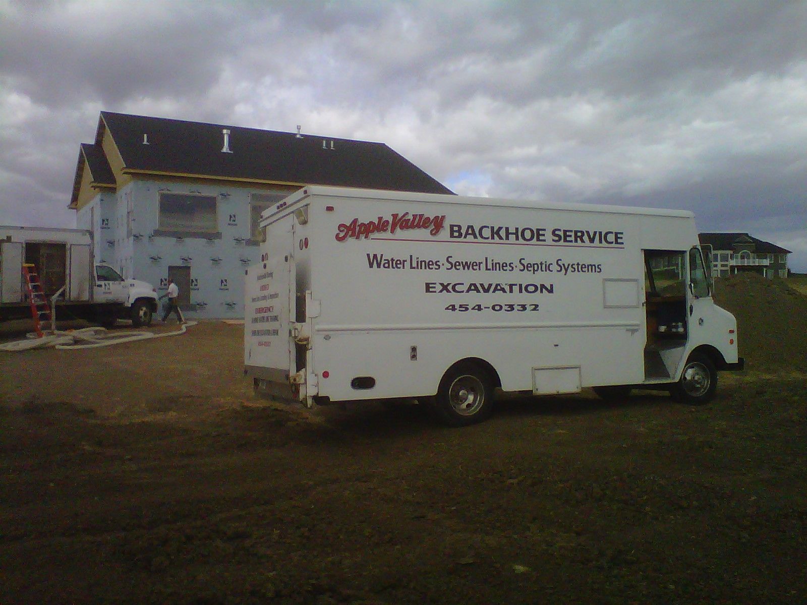 White Bachalor Service truck parked outside a building on a muddy lot.